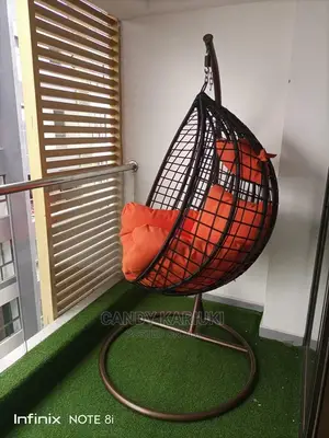 Balcony Swing With Orange Cushions and Brown Basket